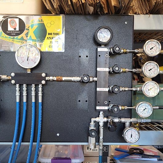 A close up of an air fill station with multiple pressure gauges and high pressure lines.