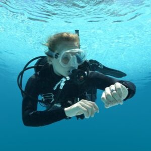 A scuba diver uses a personal dive computer to manage her dive safer than she can without one.